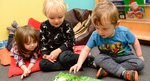 Three young children sitting and reading a book